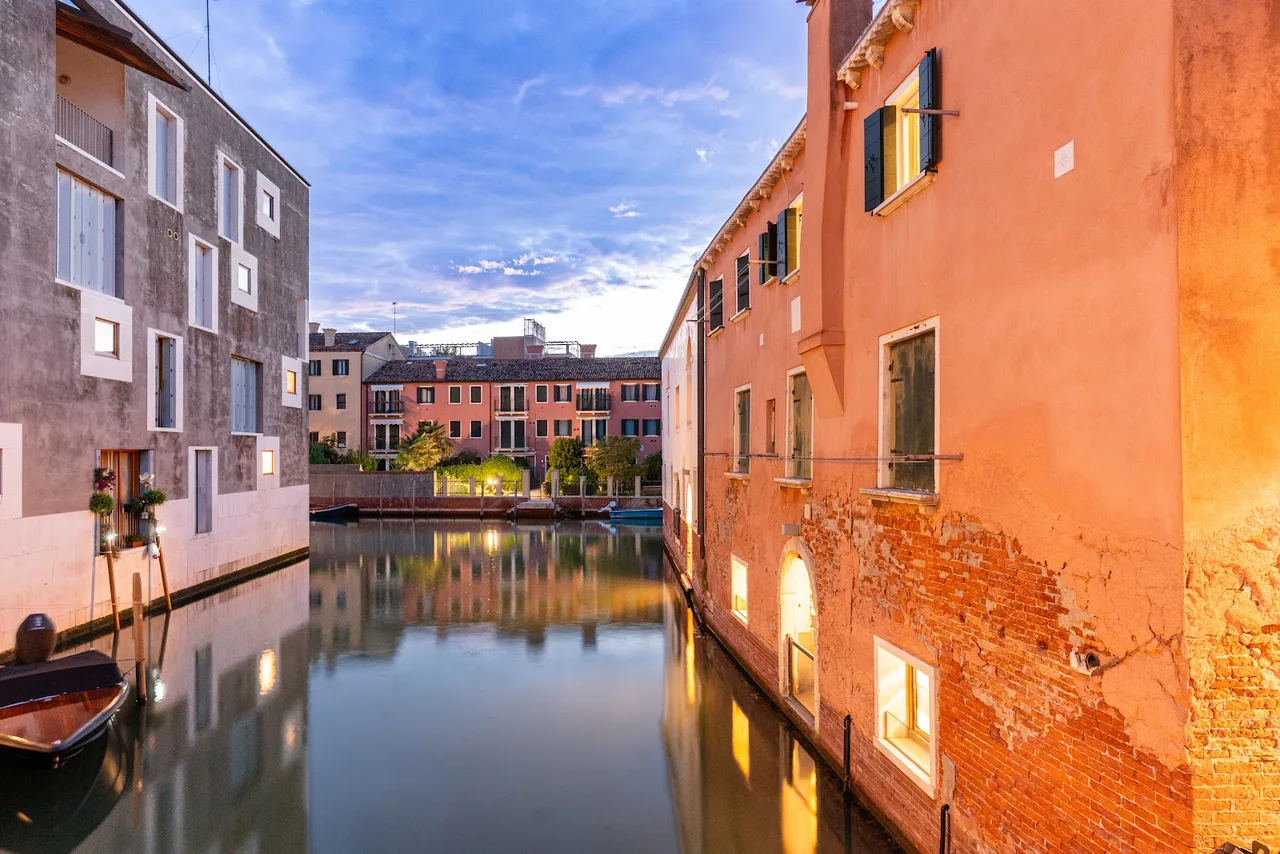Giudecca Hotel Venice private landing dock with a wooden gangway, moored outboard boats and a view across the canal to the Zattere