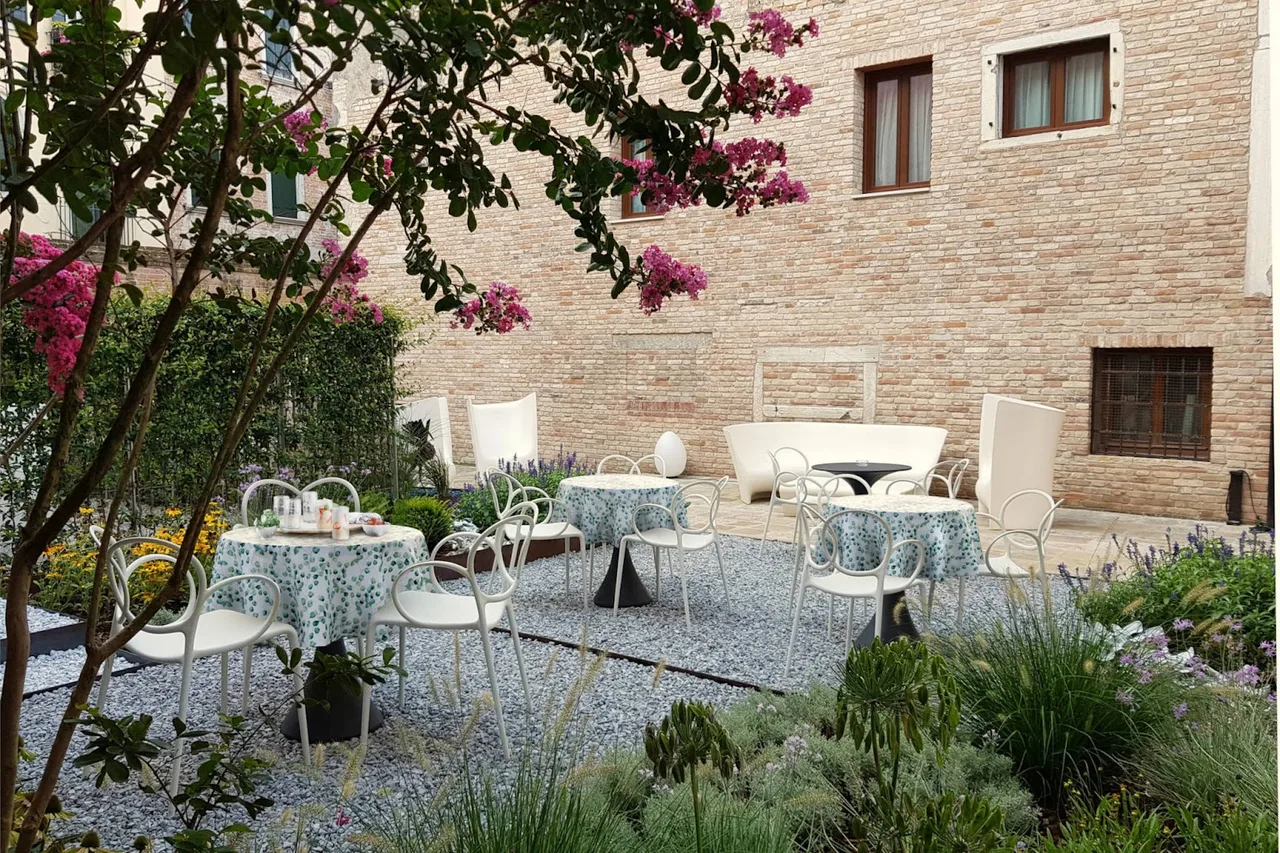 Hotel Aquarius Venice 15th-century palazzo courtyard facing Campo San Giacomo dell'Orio with a stone well and trees overhead