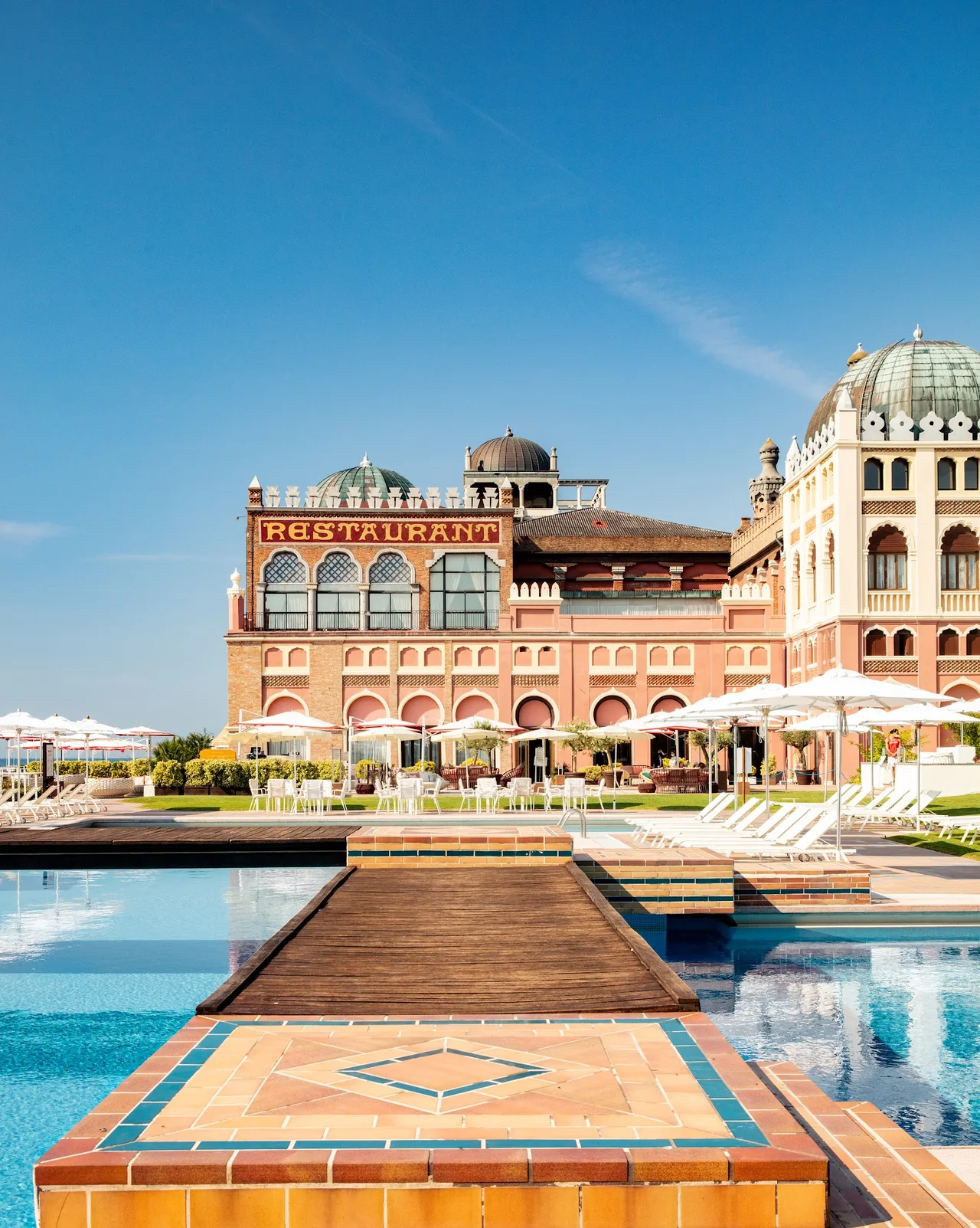 Hotel Excelsior Venice Lido Moorish-styled beachfront facade on Lungomare Marconi with turret, striped cabanas on the sand and parasols in rows