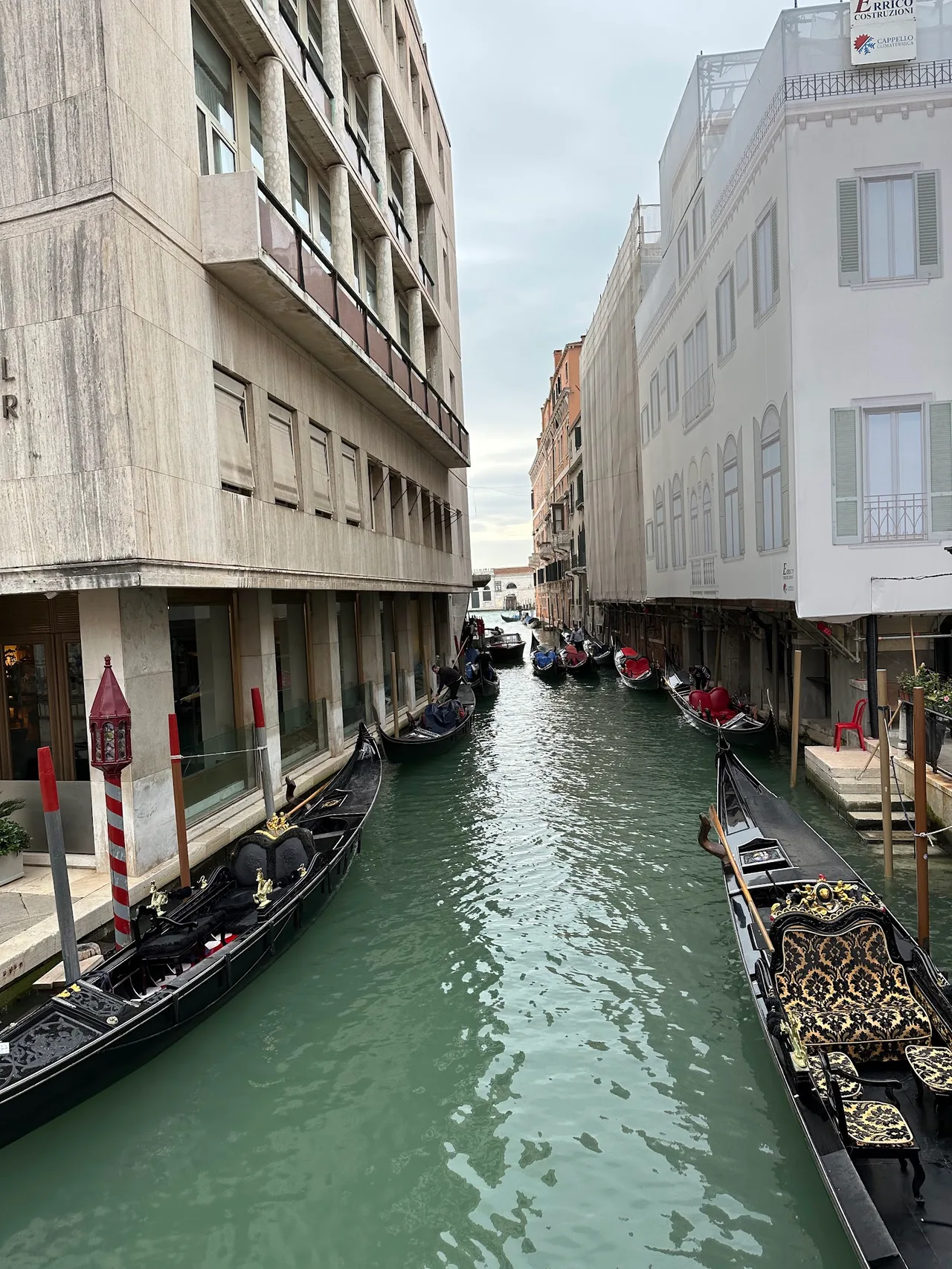 Hotel Violino D'Oro facade on a small Venetian calle with wrought-iron lamp and a pink geranium window box, overcast daylight